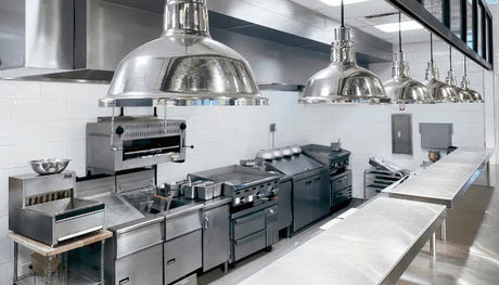 Professionelle Gastronomie-Küche mit Edelstahlgeräten, Kochfeldern und Dunstabzugshauben