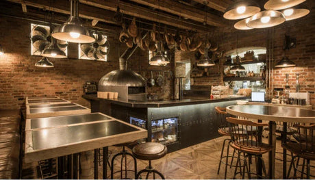 Professionelle Gastronomie-Küche mit Edelstahlmöbeln, Pizzaofen und rustikalem Ambiente